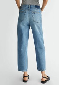 Ljusblå denimjeans med avslappnad passform, raka ben och två bakfickor. Åtföljt av svarta sandaler.