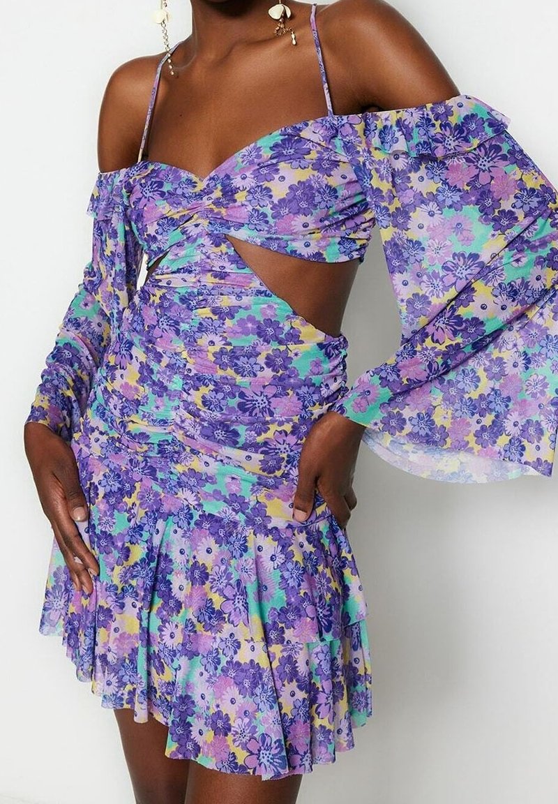 Blomstret kjole med lilla, blå og gule farver, off-shoulder design, lange ærmer, rynket tekstur og lagdelt nederdel.