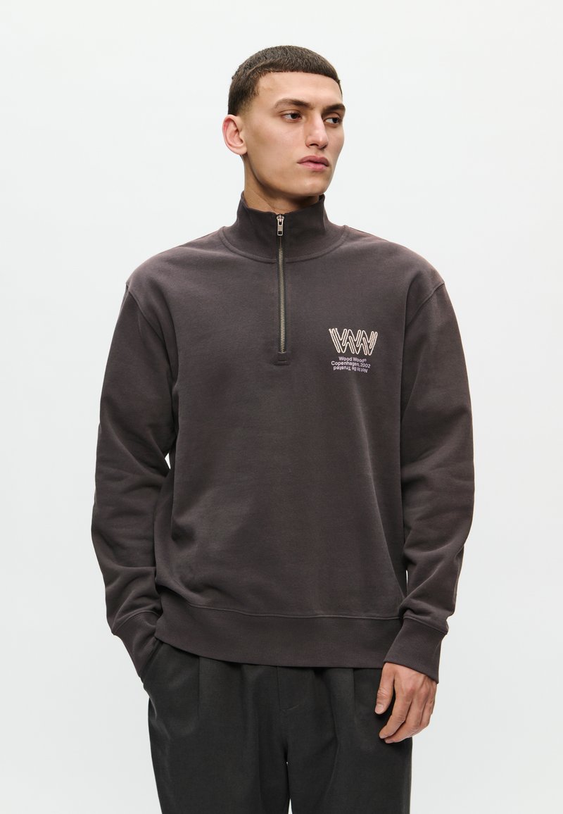 Tmavošedá mikina na zips s vysokým golierom, ktorá má logo na ľavej hrudi a ribbované manžety a spodný lem. Hladký, mäkký materiál.