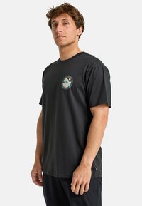 Black cotton t-shirt featuring a round neckline, short sleeves, and a circular logo patch on the chest. Smooth texture and relaxed fit.