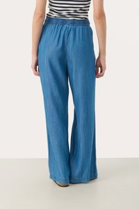 Bredda, blå denimbyxor med elastisk midja. Tyget har en slät yta och en subtil lyster, vilket ger en avslappnad passform.