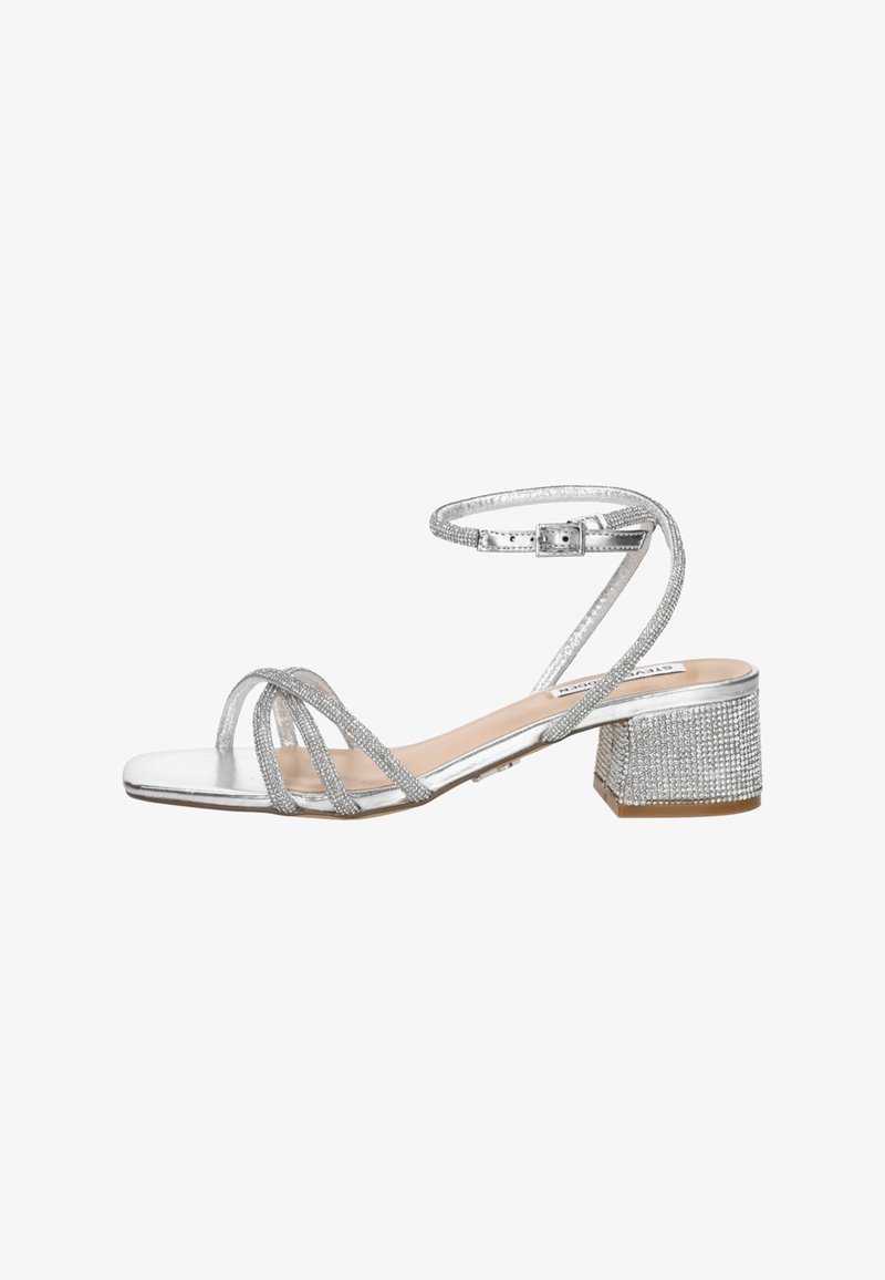 Silver strappy sandal with low block heel covered in rhinestones, buckle ankle strap, and open toe design.