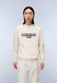 Crèmekleurige sweatshirt met een ronde hals, voorzien van een grafische logo met de Noorse vlag. Gecombineerd met bijpassende crèmekleurige cargo-broeken.