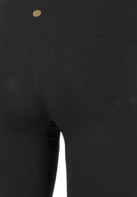 Schwarze Leggings mit glatter Textur, ausgestattet mit einem hohen Bund und einem kleinen dekorativen Logo auf der Rückseite. Einfaches, figurbetontes Design.