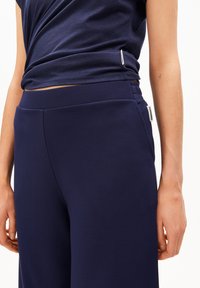 Marineblaues Freizeitkleidungs-Set bestehend aus einem weichen, strukturierten T-Shirt und hoch taillierten Hosen mit Seitentaschen und dezenten Markendetails.