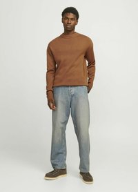 Brauner gerippter Pullover mit rundem Halsausschnitt, kombiniert mit hellblauen, lässig sitzenden Jeans und braunen Schnürstiefeln. Strukturiertes Strickdesign.