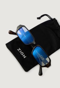 Blauw getinte rechthoekige brillen met donkere schildpad-achtige monturen, rustend op een zwarte pouch met de merknaam "ZIGN" in witte tekst.