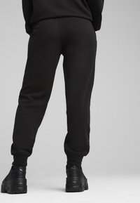 Zwarte sweatpants van zacht materiaal, met een taps toelopend design en geribde boorden. Gecombineerd met chunky zwarte sneakers.