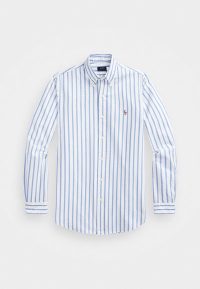 Camisa branca de botões com finas riscas azuis, apresentando um colarinho, mangas longas e um pequeno logótipo no peito. Teve um tecido de algodão suave.