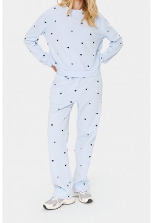 Set composto da felpa e pantaloni azzurro chiaro con piccoli motivi a cuore neri. Tessuto morbido, polsini e vita elasticizzati. Vestibilità casual e design confortevole.