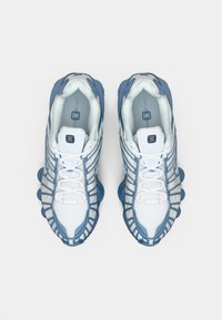 Ζευγάρι λευκών και ανοιχτό γαλάζιων αθλητικών παπουτσιών με διχτυωτό ύφασμα και έντονα μαξιλαρωμένα πέλματα, απεικονιζόμενο από πάνω σε άσπρο φόντο.