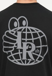 Svart T-skjorte med en stor grå grafikk som viser en globe holdt av en hånd, med "LR" og "ab" tekst integrert i designet.