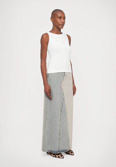 Fehér, ujjatlan felső díszítésekkel; hosszú, többszínű farmer szoknya bézs és szürke panelekből; állatmintás cipők.