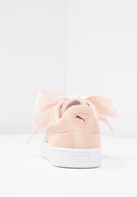 PUMA Sneaker aus weichen, pinken Wildleder mit einer weißen Gummisohle, die eine große Satinschleife und ein kleines Logo an der Ferse aufweisen.