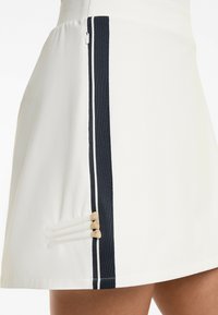 White skirt with navy side stripes and decorative wooden accents. Features smooth texture and a sleek, A-line design. Zipper on the side.