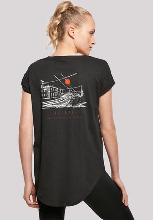 Schwarzes T-Shirt mit abgerundetem Saum, auf dessen Rückseite eine weiße Grafik einer Stadtlandschaft und eine rote Sonne zu sehen sind. Weicher Stoff mit aufgerollten Ärmeln.