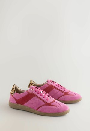 Adidași roz din suede cu accente roșii, panouri texturate și un toc cu imprimeu de leopard. Au sireturi roz și o talpă din cauciuc.