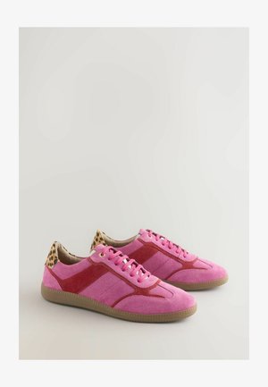 Adidași roz din suede cu accente roșii, panouri texturate și un toc cu imprimeu de leopard. Au sireturi roz și o talpă din cauciuc.