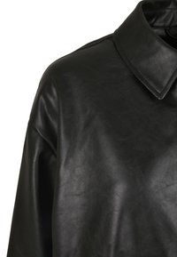 Chemise en cuir noir avec un col classique, texture lisse et coupe décontractée, avec des coutures minimales et sans détails de quincaillerie visibles.