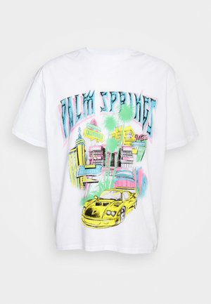 T-shirt blanc avec un graphisme coloré d'une voiture de sport jaune, des palmiers, des bâtiments et des panneaux de rue de Californie, avec un texte stylisé au-dessus.