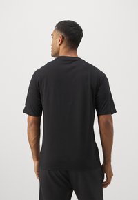 Schwarz, kurzärmliges T-Shirt aus weichem Material. Mit Rundhalsausschnitt und lockerer Passform, glatter Textur und ohne sichtbare Grafiken.