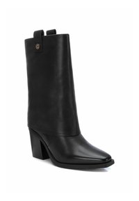 Stivaletto in pelle nera con punta affusolata, tacco a blocco e asta alta con parte superiore arrotondata e tag decorativa sul retro.