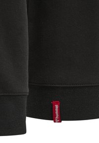 Svart sweatshirt med ribbat avslut och en liten röd etikett med varumärket "hummel" i vitt. Materialet verkar mjukt och strukturerat.