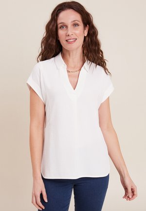 Blouse blanche à manches courtes avec col, décolleté en V profond et texture lisse. Dotée d'un ourlet arrondi et d'un design subtil et minimaliste.