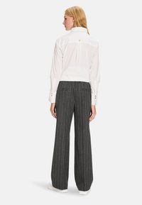 White blouse with a back yoke, buttoned cuffs, paired with gray pinstriped wide-leg trousers featuring two back pockets and soft texture.