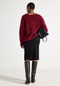 Burgundinpunainen pörröinen neule, kapea musta ribbineulehame, polviin ulottuvat ruskeat nahkasaappaat ja musta laukku. Painopiste tekstuureissa ja väri-eroissa.