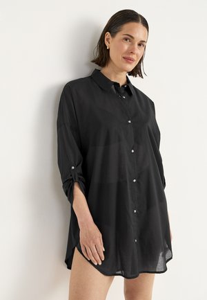 Schwarze Hemdbluse aus leichtem Stoff, mit Kragen, hochrollbaren Ärmeln mit Knöpfen und einem leicht abgerundeten Saum.