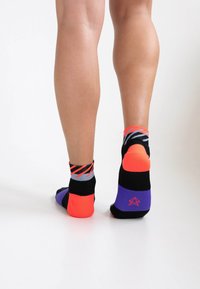 Bunte Knöchelsocken mit einer Mischung aus schwarzen, orangefarbenen, lila und grauen Mustern sowie einem Logo auf der Rückseite. Dehnbares und bequemes Material.