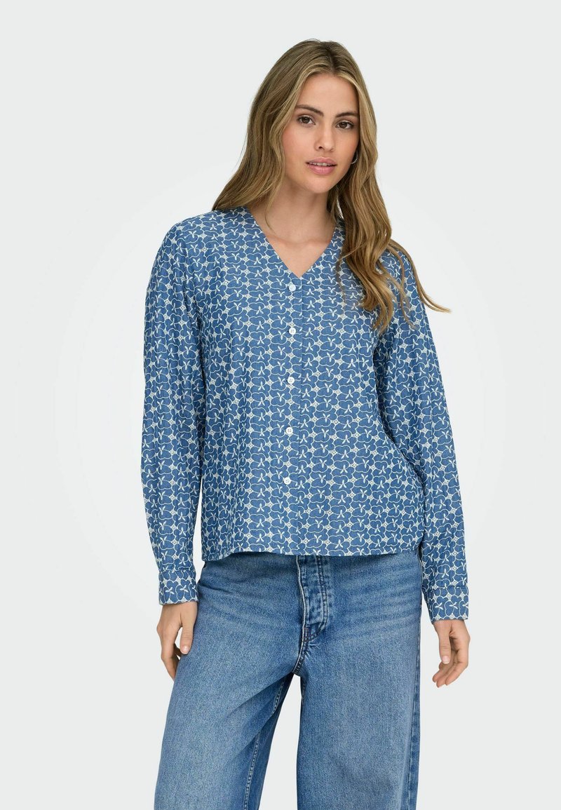 Chemise bleu à boutons avec col en V, manches longues et motif abstrait blanc. Confectionnée en tissu doux, avec une coupe décontractée.