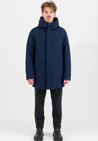 Marineblauwe parka-jas met een hoge kraag, ritssluiting en twee voorzakken. Gemaakt van een gestructureerde stof, met een capuchon en een rechte pasvorm.