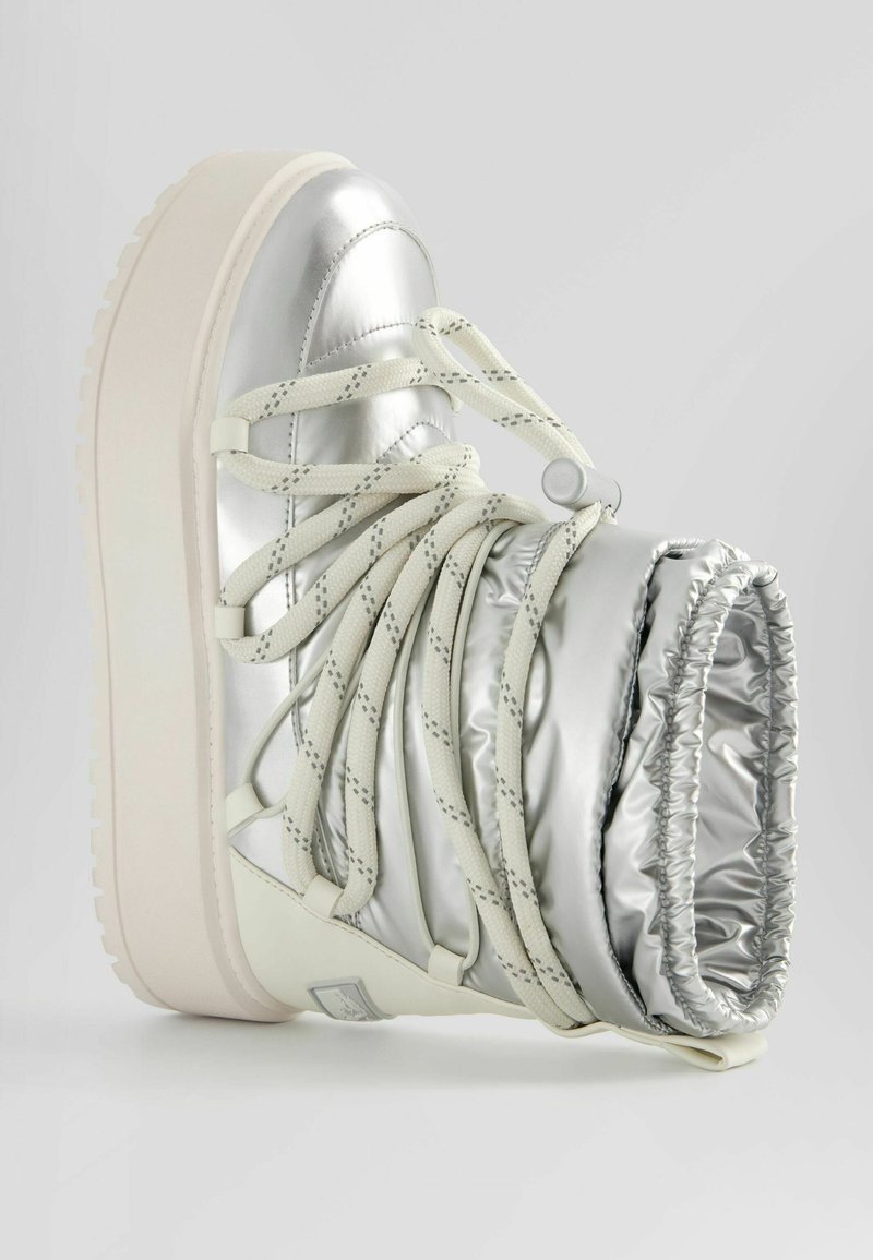 Silberne metallische High-Top-Stiefel mit gepolstertem Schaft, weißer Gummisohle und Kreuzschnürdetails. Glatte Textur mit glanzvollem Finish.