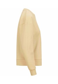 Sudadera beige clara con cuello redondo, mangas largas, corte relajado, puños y bajo acanalados, hecha de una tela suave y de textura lisa.