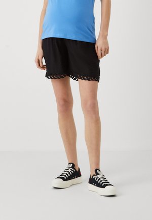 Shorts noirs avec un ourlet en dentelle festonné, en tissu texturé. Assortis avec des baskets noires et une chemise bleue.