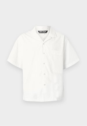 Chemise blanche à manches courtes avec boutons, col et poche poitrine, présentée sur un fond gris clair uni.