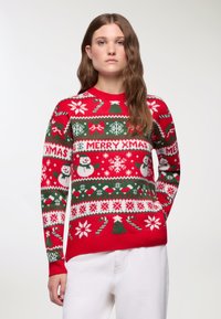 Czerwony sweter z wełny, zdobiony wzorami nawiązującymi do Świąt Bożego Narodzenia, w tym bałwankami, płatkami śniegu, laskami cukrowymi i napisem "WESOŁYCH ŚWIĄT". Ściągacze na rękawach.