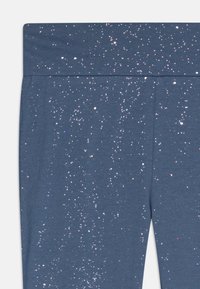Leggings azul-marinho com um padrão estrelado e pontos metálicos. Tecido suave e elástico com uma cintura larga.