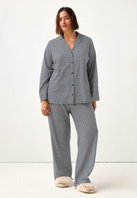 Set di pigiama a righe con top button-up, colletto e maniche lunghe, abbinato a pantaloni larghi. Realizzato in tessuto morbido.