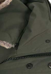 Groene stoffen jas met een nepbonten kraag, voorzien van een ritssluitingzak, zwarte rits en knoopsluitingen voor een veilige bevestiging.