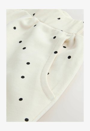 Kreemikõrvale kangas mustade täppidega; varustatud veniva vöökohaga ja küljetaskutega; pehme tekstuur ja sile viimistlus.