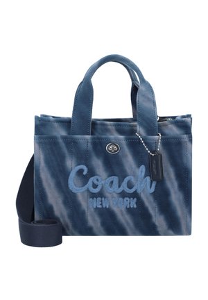 Petit sac cabas en tissu bleu avec poignées et bandoulière, brodé "Coach New York" sur le devant et une petite étiquette suspendue à une chaîne.