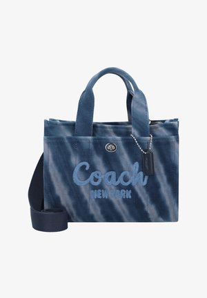 Kleine blaue Stofftragetasche mit Griffen und Schultergurt, vorne bestickt mit "Coach New York" und einem kleinen Anhänger an einer Kette.