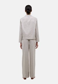 Ensemble en tissu léger rayé, comprenant une veste sans col et un pantalon à jambe large avec une texture lisse et un liseré contrastant aux poignets.