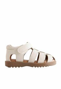 Hvide stofsandaler med åbne sider, der har flere stropper og velcro-lukning. Sålen er brun og struktureret for bedre greb.