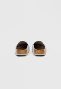 Grå slippers med korkdetalj på hælen, åpen bak, og strukturert overflate. Flate såler for komfort og enkel bruk.