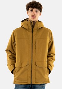 Giacca cappuccio gialla-marrone con zip frontale, due ampie tasche frontali e tessuto testurizzato. Design minimalista con linee pulite.