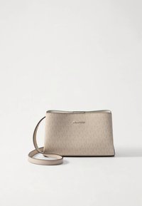 Bolso cruzado beige claro con un acabado texturizado, que cuenta con una correa delgada para el hombro y un detalle metálico de logotipo en la parte frontal.